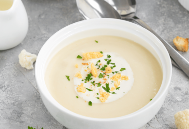 Bol de soupe de chou-fleur crémeuse, décorée de croutons dorés et d’un filet d’huile d’olive.