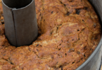 Gâteau moelleux aux dattes découpé, garni de noix concassées et servi avec un thé.