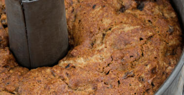 Gâteau moelleux aux dattes découpé, garni de noix concassées et servi avec un thé.