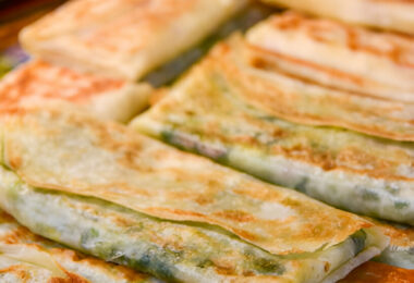 Galettes salées dorées et croustillantes, garnies d'oignon vert et de fromage fondu