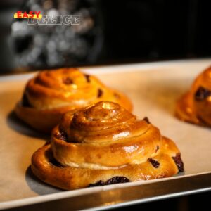 Pains aux raisins maison dorés et feuilletés, garnis de crème pâtissière et raisins.