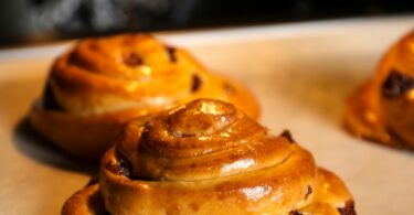 Pains aux raisins maison dorés et feuilletés, garnis de crème pâtissière et raisins.