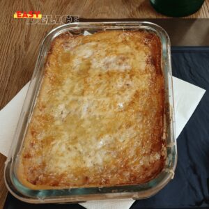 Gratin de pommes de terre et épinards doré au four, servi dans un plat blanc.