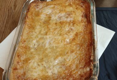 Gratin de pommes de terre et épinards doré au four, servi dans un plat blanc.