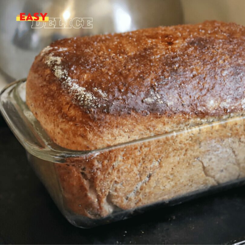 Pain rustique moulé doré avec une mie aérée, posé sur une planche en bois.