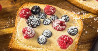 Custard toast doré et garni de fruits frais, servi sur une assiette.