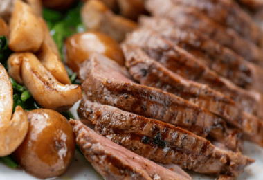 Rôti de bœuf cuit à l’airfryer, prêt à être tranché et servi avec des légumes rôtis.