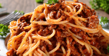 Spaghettis bolognaise servis dans un plat, garnis de parmesan et de persil frais.