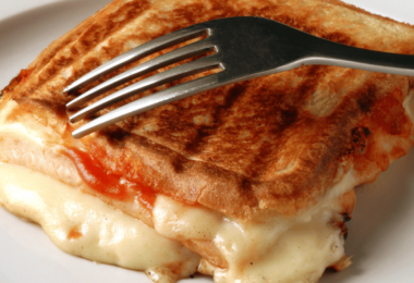 Croque-monsieur doré et croustillant cuit à la poêle, prêt à être dégusté avec une salade verte.