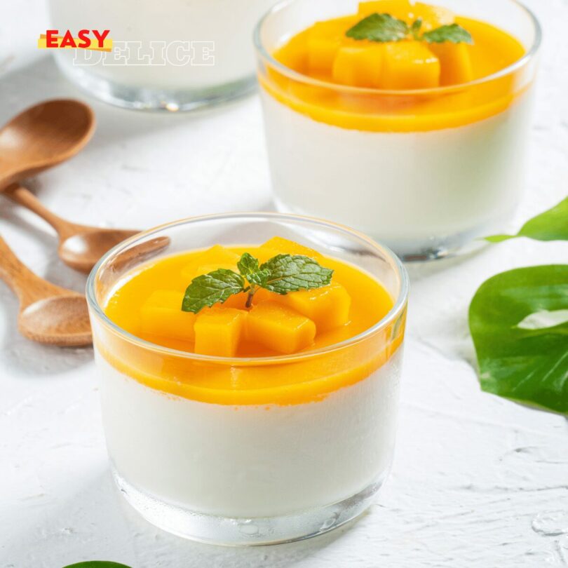 Verrine de panna cotta à la mangue, surmontée de purée de mangue fraîche, décorée de feuilles de menthe.