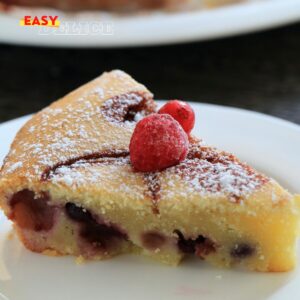 Clafoutis aux fruits moelleux, cuit dans un moule à l’Airfryer, saupoudré de sucre glace.