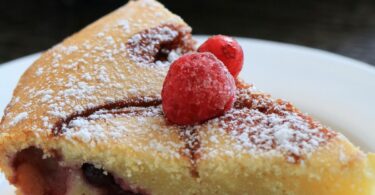 Clafoutis aux fruits moelleux, cuit dans un moule à l’Airfryer, saupoudré de sucre glace.