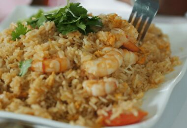 Riz sauté thaï aux légumes et crevettes servi dans un bol avec des herbes fraîches.