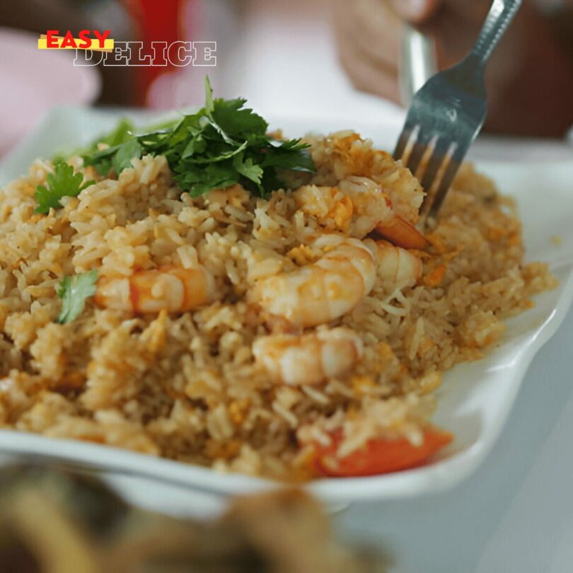 Riz sauté thaï aux légumes et crevettes servi dans un bol avec des herbes fraîches.