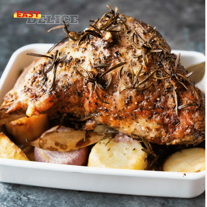 Épaule d'agneau entière rôtie au four, dorée et juteuse, servie avec des pommes de terre.