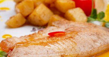 Filet de poisson grillé servi avec citron, persil frais et légumes grillés.