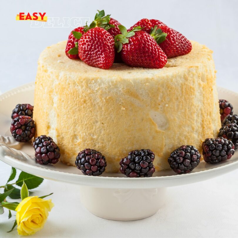 Gâteau des anges aérien, tranché, accompagné d’un coulis de fruits rouges et de menthe fraîche.