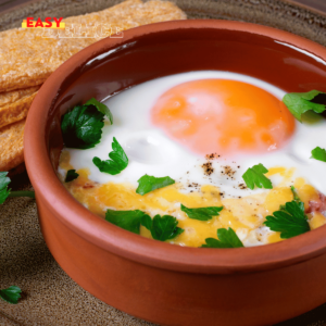 Œufs cocotte au chèvre et aux lardons servis dans des ramequins avec pain grillé.