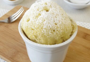 Mugcake au citron doré, moelleux et servi avec du sucre glace et des zestes de citron.