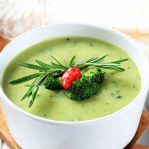 Bol de velouté de brocoli et truite garni de persil frais sur une table rustique.