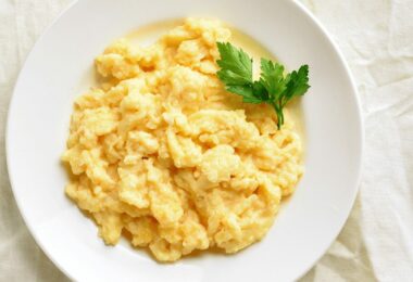 Brouillade d’œufs crémeuse servie dans une assiette avec du pain grillé.