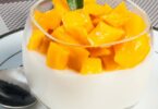 Panna cotta à l’orange et à la mangue dans une verrine, nappée de coulis.