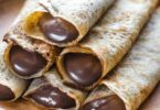 Crêpes dorées garnies de Nutella et pliées sur une assiette avec une touche de sucre glace.