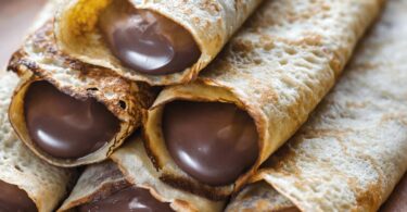 Crêpes dorées garnies de Nutella et pliées sur une assiette avec une touche de sucre glace.