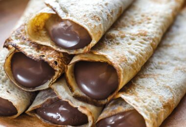 Crêpes dorées garnies de Nutella et pliées sur une assiette avec une touche de sucre glace.