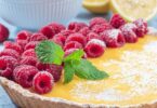Tarte au citron au mascarpone tranchée sur une assiette, décorée de zeste.