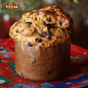 Panettone maison doré avec raisins secs et écorces d’orange sur une table festive