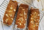 Banana bread sans sucre tranché sur une planche, décoré de noix.