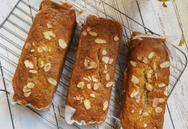 Banana bread sans sucre tranché sur une planche, décoré de noix.