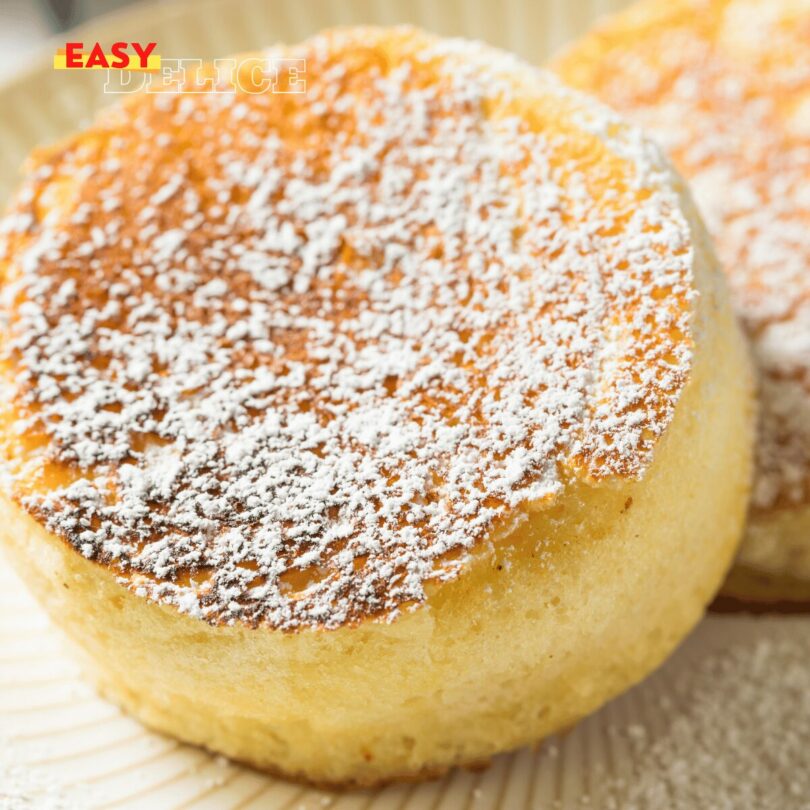 Pancakes soufflés japonais dorés servis avec sucre glace sur une assiette blanche.