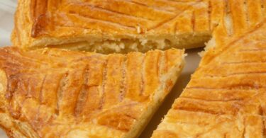 Galette des rois de Cyril Lignac dorée avec motifs en rosace sur une table festive