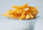 Frites surgelées dorées et croustillantes sorties de l’airfryer, servies dans un panier métallique.