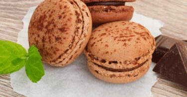 Macarons au chocolat avec ganache brillante empilés sur une assiette blanche