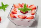 Yaourt maison à la fraise servi dans un pot en verre avec des morceaux de fraises fraîches