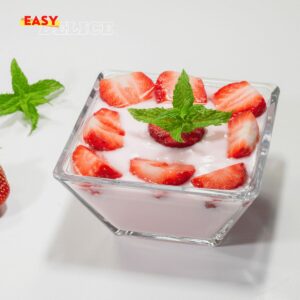 Yaourt maison à la fraise servi dans un pot en verre avec des morceaux de fraises fraîches