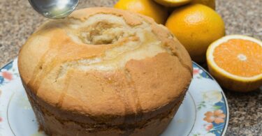 Cake à l’orange moelleux avec un glaçage brillant et des zestes d’orange.