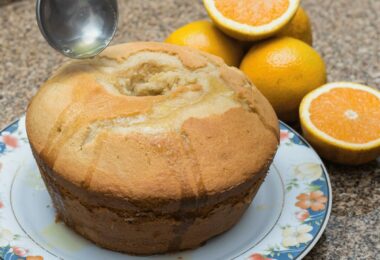 Cake à l’orange moelleux avec un glaçage brillant et des zestes d’orange.