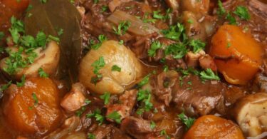 Assiette de bœuf bourguignon avec une sauce onctueuse et des légumes fondants.