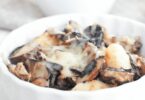 Gratin de gnocchi doré avec des champignons et des lardons, servi dans un plat à gratin.