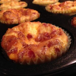 Mini quiches dorées au poulet et dinde fumée, servies sur une assiette avec une salade verte.