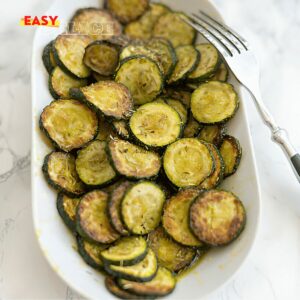 Courgettes rôties dorées et croustillantes, assaisonnées aux herbes et servies dans une assiette.