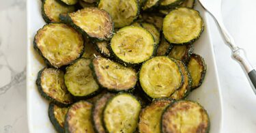 Courgettes rôties dorées et croustillantes, assaisonnées aux herbes et servies dans une assiette.