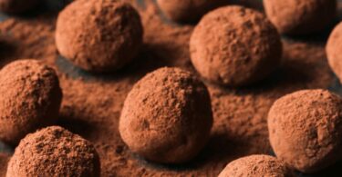 Truffes au chocolat roulées dans du cacao, présentées sur une assiette festive.