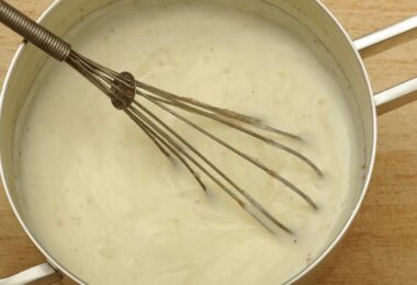 Sauce béchamel onctueuse servie dans un bol avec une cuillère en bois.