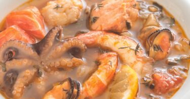 Assiette de bouillabaisse servie avec sa rouille et ses croûtons dorés.