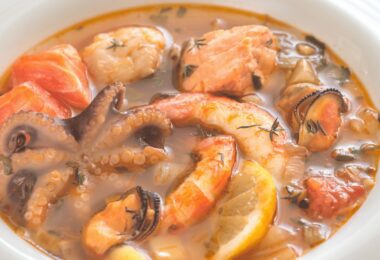 Assiette de bouillabaisse servie avec sa rouille et ses croûtons dorés.